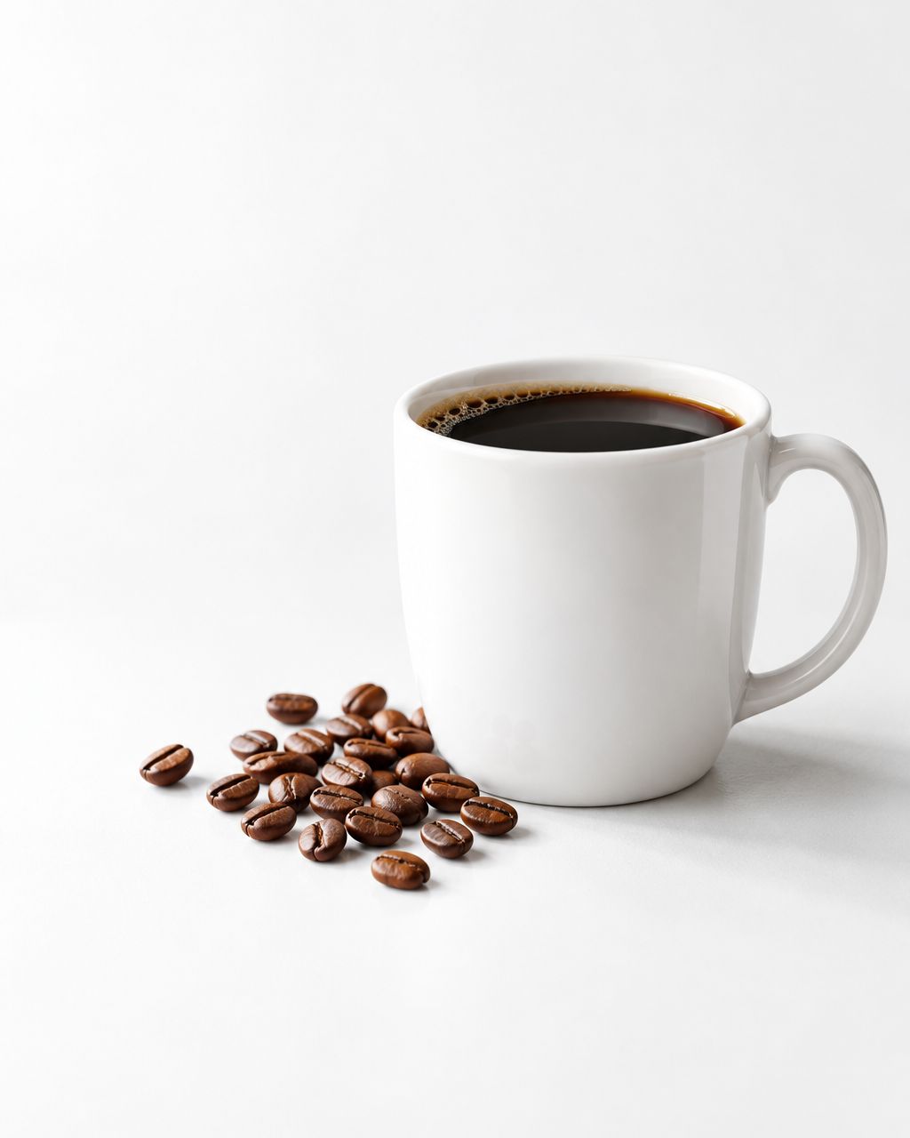 A white mug of black coffee beside medium-roasted coffee beans on a bright studio surface